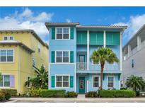 Two-story light blue house with teal accents, a balcony, and palm trees at 3056 Parrot Head Pl, Kissimmee, FL 34747