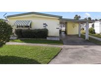 Cute yellow mobile home with carport and landscaped yard at 115 Palm Dr, Eustis, FL 32726