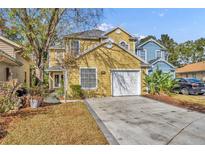 Two-story yellow house with white garage door and landscaping at 1445 Creekside Cir, Winter Springs, FL 32708