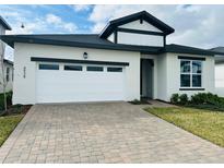 Modern two-story home with white exterior, two-car garage, and paver driveway at 4934 Shady Pines Dr, St Cloud, FL 34772