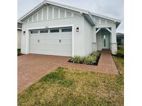 Two-car garage and light-colored house with a landscaped yard at 5031 Dancy Ln, St Cloud, FL 34772