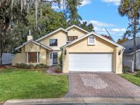 Charming two-story home with a white garage door, brick driveway, and landscaped yard at 631 Fallsmead Cir, Longwood, FL 32750