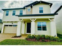 Two-story house with a beige exterior, landscaped yard, and two-car garage at 4946 Shady Pines Dr, St Cloud, FL 34772