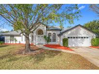 White house with red mulch beds, two-car garage, and landscaping at 9095 Palos Verde Dr, Orlando, FL 32825