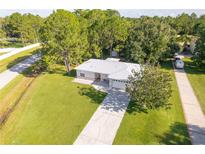 Aerial view of a single-story home with a driveway, attached garage, and lush green lawn at 1469 Swan Pl, Kissimmee, FL 34759
