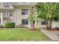 Front exterior view of a two-story condo with a green lawn and trees at 6030 Village Cir, Orlando, FL 32822