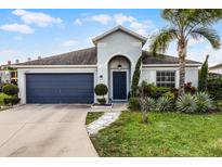 Charming single-story home with a dark blue garage door and lush landscaping at 2213 Grantham Ave, Davenport, FL 33837