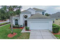 Two-story house with a white garage door and landscaping at 8100 Fan Palm Way, Kissimmee, FL 34747