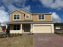 Two-story house with beige siding, a gray door, and a brick driveway at 1659 Andover Ridge Dr, Deland, FL 32720