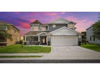 Two-story house with gray siding, a large garage, and a well-manicured lawn at 2377 Victoria Dr, Davenport, FL 33837