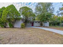 Tan single-story house with red door and driveway at 5815 Harrington Dr, Orlando, FL 32808