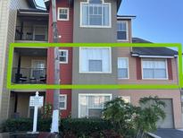 Two-story condo building with red and tan exterior, balconies, and parking at 2208 Antigua Pl # 924, Kissimmee, FL 34741
