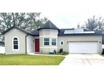 Attractive one-story house with a red door, solar panels, and a two-car garage at 612 Parakeet Ct, Kissimmee, FL 34759