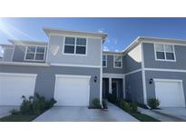 Two-story townhome with gray siding, white garage doors, and landscaping at 2774 Bright Bird Ln, Winter Park, FL 32792