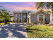 Two-story house with gray exterior, paver driveway, and lush landscaping at 9168 Lake Avon Dr, Orlando, FL 32829