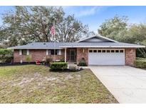 Brick ranch home with attached garage and landscaped yard at 9830 Jackson Rd, Leesburg, FL 34788