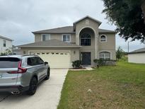 Two-story house with a large yard and a two-car garage at 1403 Kissimmee Ct, Kissimmee, FL 34759