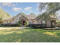 One-story home with stone accents, red door, and landscaped lawn at 25628 Hawks Run Ln, Sorrento, FL 32776