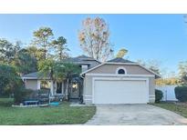 Tan house with white garage door and landscaped yard at 1022 Bartlett Ct, Oviedo, FL 32765
