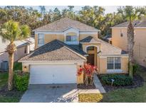 Two-story house with a tan exterior, white garage door, and landscaping at 8458 Secret Key Cove, Kissimmee, FL 34747