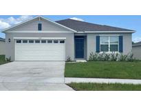 Single-story home with white garage door and blue shutters at 1008 Bear Hammock Dr, Umatilla, FL 32784