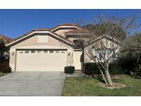 Tan two-story house with a beige garage door and landscaping at 5453 Shingle Creek Dr, Orlando, FL 32821