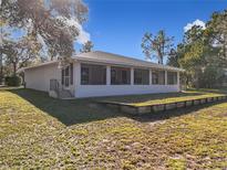 Newly renovated house exterior boasts a screened patio and expansive grassy yard at 23917 Kays Way, Astatula, FL 34705