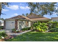 One-story home with brick accents, screened porch, and landscaped yard at 24946 Cranes Roost Circle, Leesburg, FL 34748