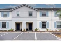 Two-story townhome with light gray siding and blue shutters, two-car parking at 7424 Oakmoss Loop, Davenport, FL 33837