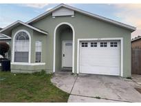 Light green house with white garage door and landscaping at 147 Dahlia Village Cir # Ge, Orlando, FL 32807