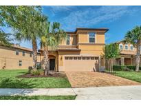 Two-story house with tan exterior, paver driveway, and landscaping at 1804 Gobi Dr, Kissimmee, FL 34747