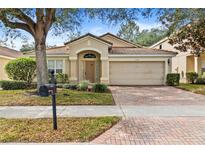 Tan house with brick driveway and landscaping at 6163 Froggatt St, Orlando, FL 32835