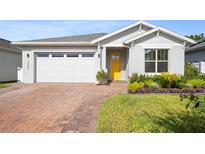 One-story home with gray siding, yellow door, and brick paver driveway at 7409 Wing Span Way, Harmony, FL 34773