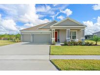 Single-story home with two-car garage, landscaped lawn, and inviting front porch at 6115 Claystone Way, Mount Dora, FL 32757