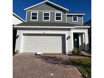 Two-story home with gray siding, white garage door, and landscaping at 1992 Heart Lake Dr, Groveland, FL 34736