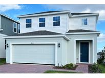 Two-story house with white and light-green siding, two-car garage, and landscaping at 6858 Spanish Imperial St, Howey In The Hills, FL 34737