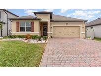 Tan one-story house with red shutters, two-car garage, and landscaped yard at 1380 Clear Brook Pl, St Cloud, FL 34772