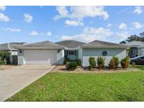 Single-story home with light blue exterior, attached garage, and well-maintained lawn at 1409 Lake Marion Dr, Apopka, FL 32712