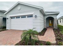 Single-story home with gray exterior, two-car garage, and landscaped walkway at 3156 Songbird Cir, Harmony, FL 34773