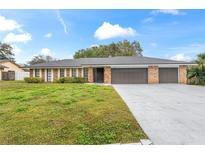 Brick house with 3-car garage, and a spacious lawn at 6829 Bittersweet Ln, Orlando, FL 32819