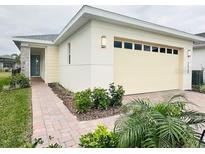 Two-car garage, light-colored exterior, and landscaped walkway at 7520 Castlewood Ct, Harmony, FL 34773