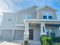 Two-story house with gray siding, stone accents, and a two-car garage at 10118 Storey Grove Way, Winter Garden, FL 34787
