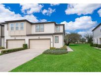 Two-story townhome with two-car garage, landscaped lawn, and charming exterior at 664 Benoi Dr, Davenport, FL 33896