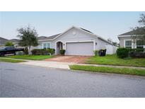 Single-story home with gray exterior, brick driveway, and landscaping at 975 Benjamin Trl, Davenport, FL 33837