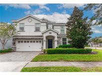 Two-story house with white and stone exterior, three-car garage, and landscaped lawn at 1550 Observer Ln, Davenport, FL 33896