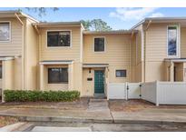 Tan two-story townhouse with green door, white fence, and landscaping at 2209 Tipperary Ct # 1, Orlando, FL 32812