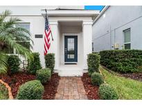 Front entry with brick walkway, American flag, and lush landscaping at 12128 Illustration Dr, Orlando, FL 32832