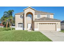 Two-story house with beige exterior, two-car garage, and manicured lawn at 415 Big Sioux Ct, Kissimmee, FL 34759