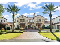 Stunning stone house with red tile roof, palm trees, and a brick driveway at 5271 Isleworth Country Club Drive, Windermere, FL 34786