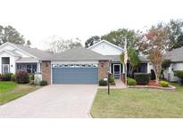 Single-story home with gray garage door, landscaping, and paved driveway at 25001 Cranes Roost Cir, Leesburg, FL 34748